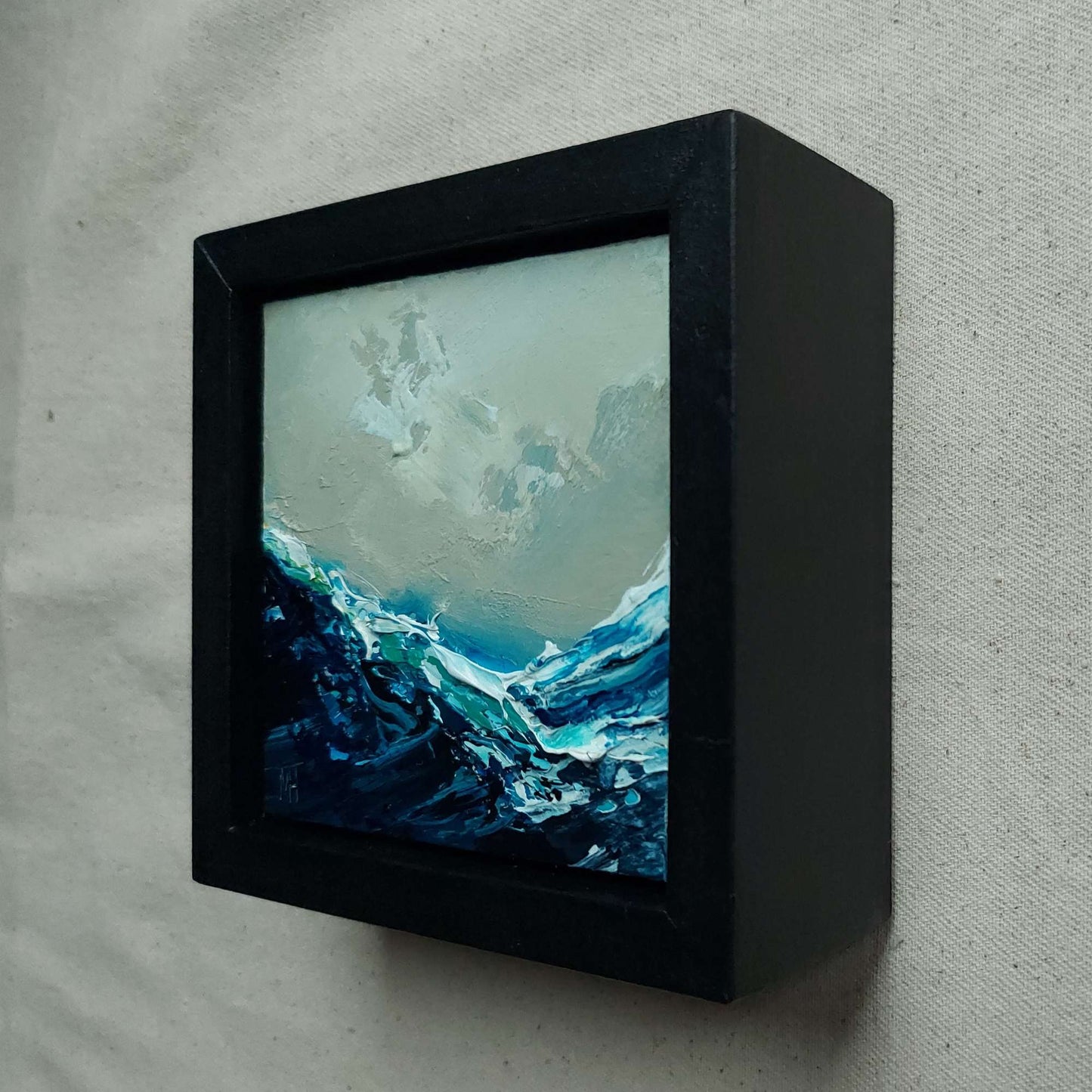 Framed abstract artwork with blue and white tones on a grey background