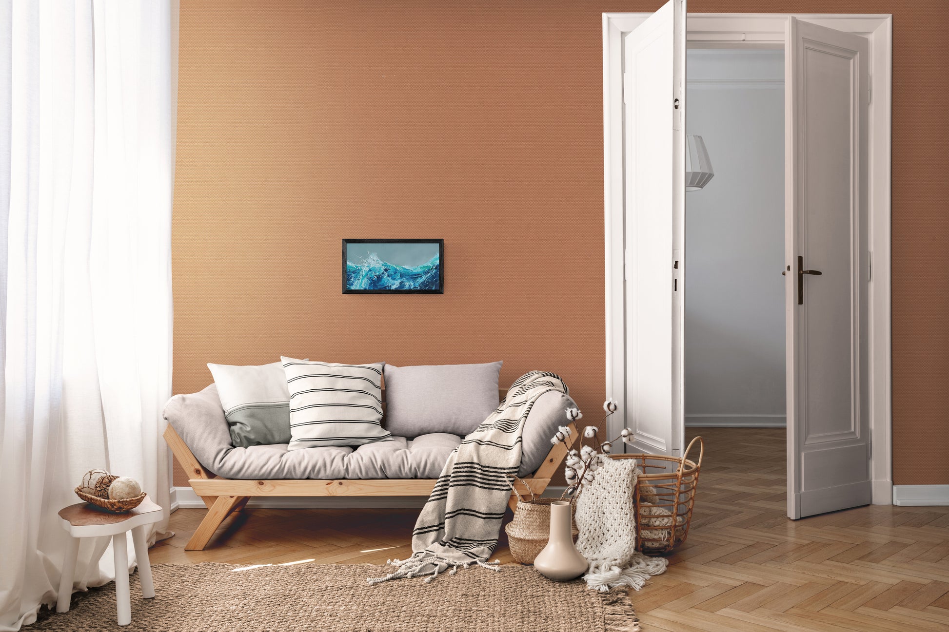 Living room with a sofa, coffee table, and decorative items against a brown wall showing an oil painting by Michael Hemming.
