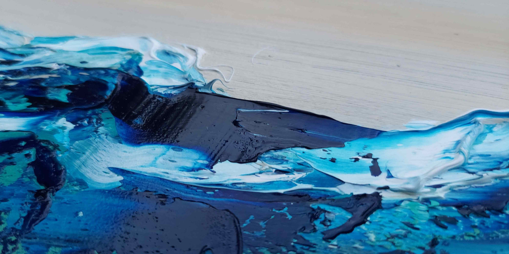 Close-up of a wave painting with blue and black abstract strokes on a textured surface.