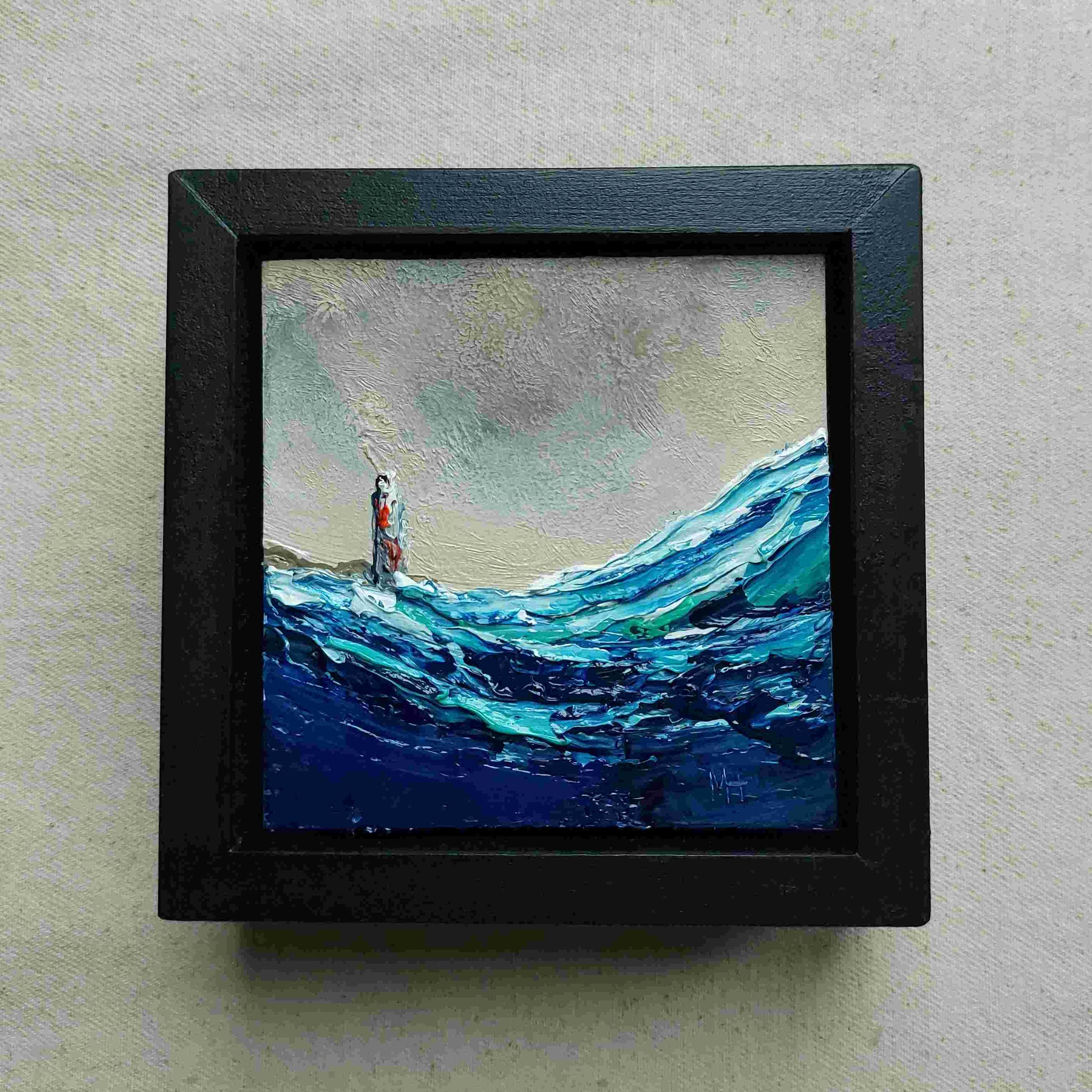 Framed painting of a lighthouse in the distance with waves.