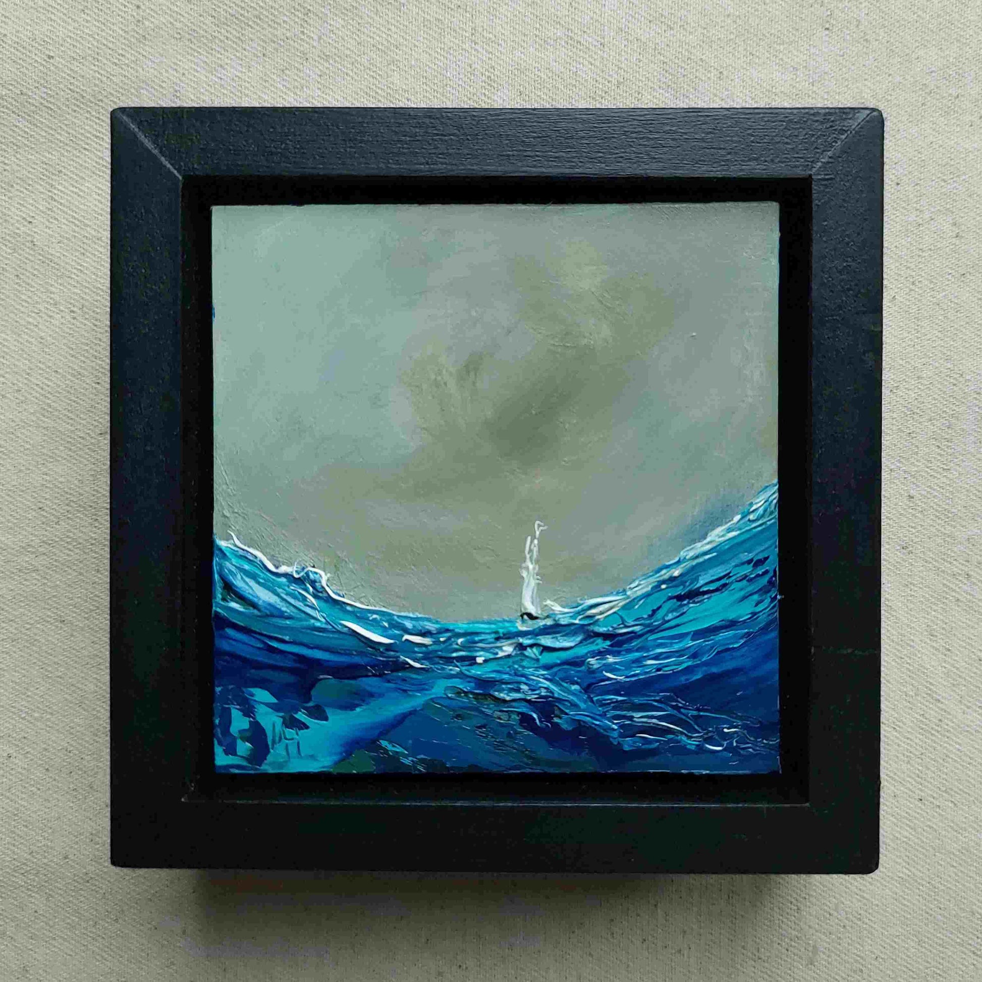 Framed painting of a sailing boat amidst large waves with a dark sky.