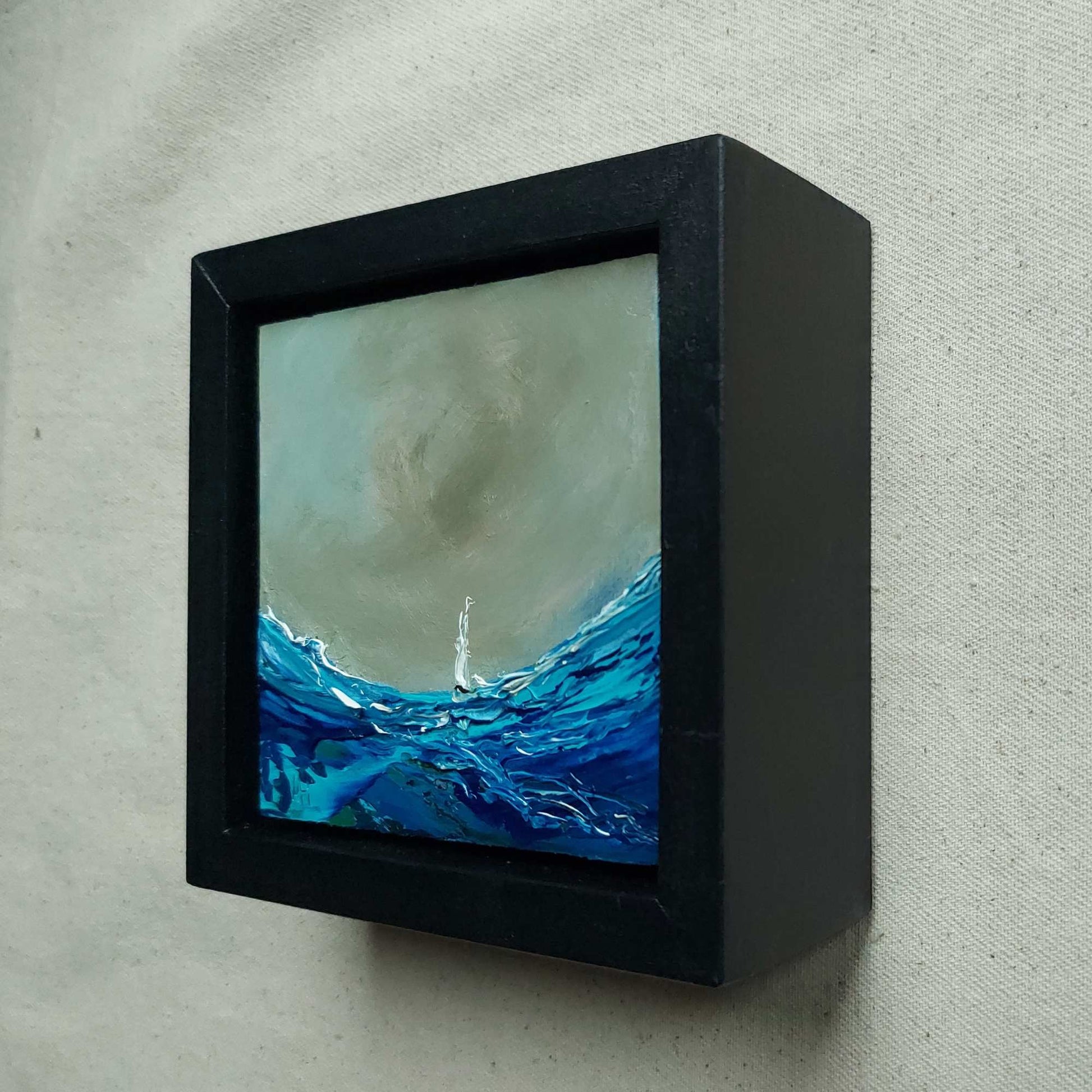 Framed depiction of a sailing boat amidst large waves with a dark sky. Viewed from the side.