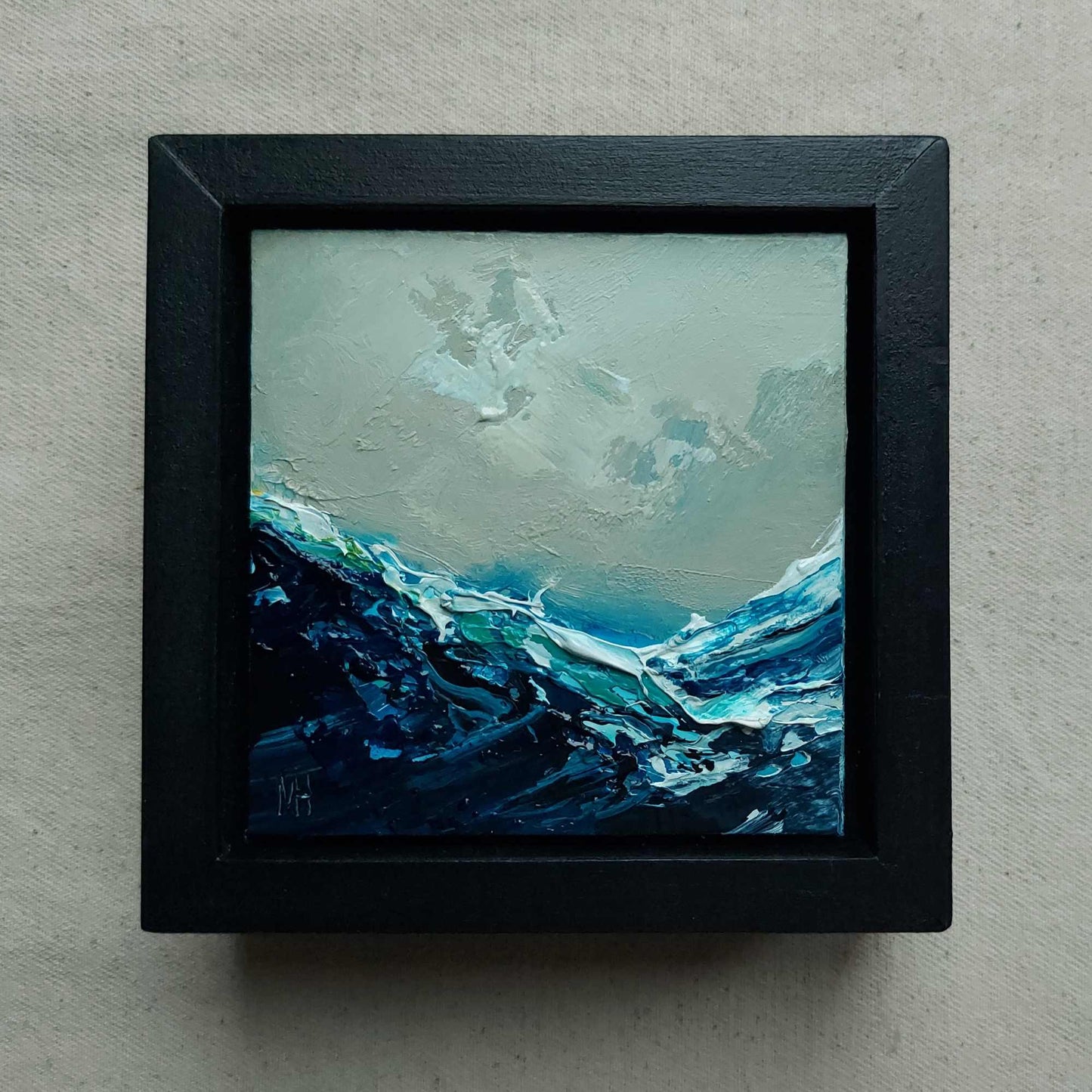 Small abstract painting in a black frame on a grey background