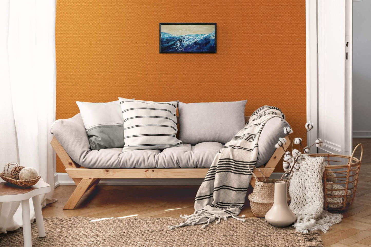 Living room with a gray sofa, striped pillow, and decorative items against an orange wall.